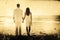 Composite image of attractive couple holding hands and watching the waves