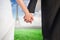 Composite image of close up of cute young newlyweds holding their hands