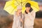 Composite image of couple sneezing in tissue while standing under umbrella