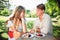 Composite image of cute couple having champagne and desert in the park