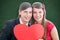 A Composite image of cute geeky couple smiling and holding heart