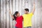 Composite image of excited couple cheering in red and yellow tshirts