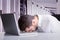 Composite image of exhausted businessman sleeping head on laptop