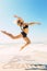 A Composite image of fit blonde jumping gracefully on the beach