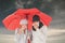 Composite image of ill couple sneezing in tissue while standing under umbrella