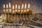 Composite image of menorah with glittering candles and western wall in Jerusalem.