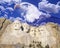 Composite image of Mount Rushmore, bald eagle, and blue sky with white clouds