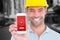 Composite image of portrait of smiling handyman showing smart phone