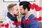 Composite image of red hanging heart and homosexual couple kissing