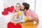 Composite image of red hanging hearts and couple kissing while having coffee