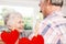 Composite image of red hanging hearts and senior couple dancing at home