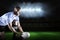 Composite image of rugby player looking away while keeping ball on kicking tee