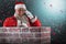 Composite image of santa claus standing beside chimney and talking on mobile phone