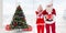 Composite image of santa and mrs claus smiling at camera offering gift