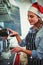Composite image of side view of waitress wearing santa hat using espresso maker