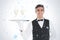 Composite image of smiling attractive waiter holding a tray with champagne glasses on it