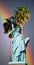 Composite image of the Statue of Liberty and pedestal against palm trees and rainbow