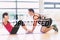 A Composite image of trainer helping woman do abdominal crunches in gym