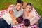 Composite image of two friends touching their glasses while raised during a picnic