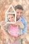 Composite image of young couple hugging and holding house outline