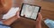 Composite of woman sitting at table with face mask, watching basketball game on tablet