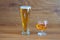 Composition of alcoholic drinks with glass of whiskey and glass of clear beer on stage of oak tables