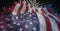 Composition of american flag billowing over red, white and blue fireworks in night sky