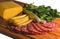 Composition of appetizing sausage, cheese, greens and onions on a wooden board, isolate