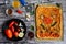 Composition of appetizing vegetable pizza, metal plate with tomatoes, pepper and garlic, spice jars and basil leaves on a wooden