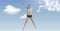 Composition of athletic woman jumping and raising hands over blue sky with clouds