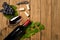 Composition with bottle and glass of wine with grape bunch and vine leaves on wooden background. Top view with copy space