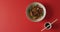 Composition of bowl of stir fry noodels with soy sauce and chopsticks on red background