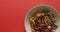 Composition of bowl of stir fry noodels with soy sauce and chopsticks on red background