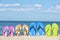 Composition with bright flip flops on sand near sea. Beach accessories