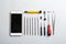 Composition with broken mobile phone and repair tools on white background