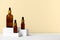 Composition brown glass bottles with aromatic natural essential oil. Cosmetic product on white geometric podium. Alternative