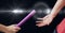 Composition of caucasian athletes passing pink relay baton with glowing light