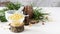 composition of cedar oil with pine nuts on a background of a branch with a pine cone, on a light wooden background