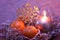 Composition Christmas with round burning candle, decorative gold snowflake and tangerines in lilac tones
