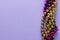 Composition of colourful mardi gras beads on lilac background with copy space