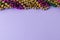 Composition of colourful mardi gras beads on lilac background with copy space