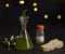 Composition with cruet of new extra virgin olive oil, salt, slice of bread and olive branch on black background and bokeh lights