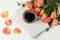 Composition with cup of coffee, notebooks and pink roses on white background