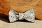 Composition: Extravagant beige with a black fine pattern of a bow tie, a wooden cut on a beige background.