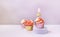 Composition with festive cupcakes with pink cream and a candle on a pink background.