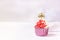 Composition with festive cupcakes with pink cream and a candle on a pink background.