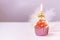 Composition with festive cupcakes with pink cream and a candle on a pink background.