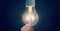 Composition of finger touching lit light bulb on blue background