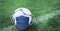 Composition of football with face mask on grass with copy space