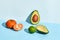 Composition of fresh fruits, mandarin lime and two halfs of cutted avocado on two-colored background